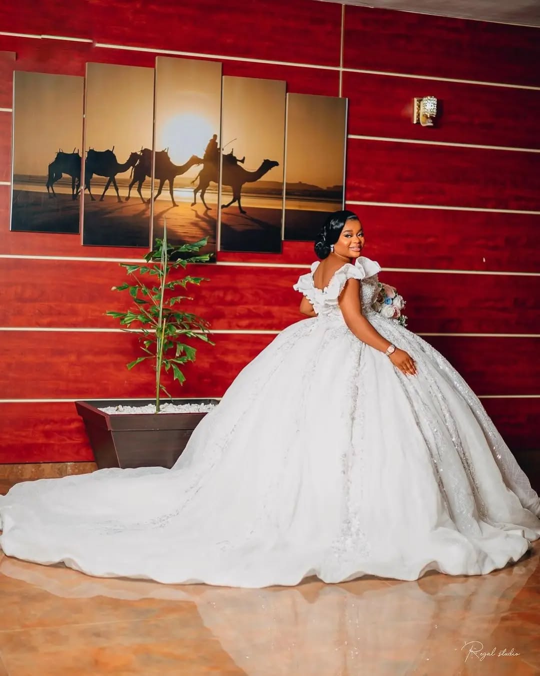 Bride with a full cathedral train against a red wall