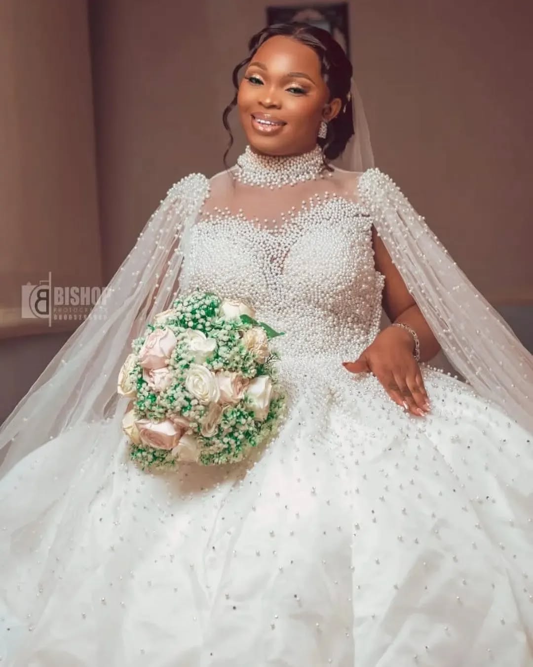 Bride in a pearl-encrusted gown with a beaded cape veil